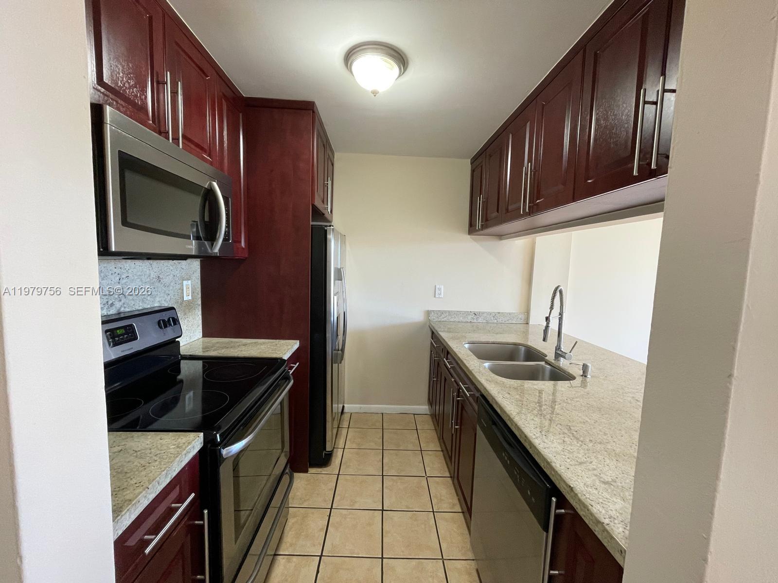 8002 Southwest 149th Avenue, Unit B409 Miami, FL 33193 - Photo 3 of 23 a kitchen with granite countertop stainless steel appliances and wooden cabinets