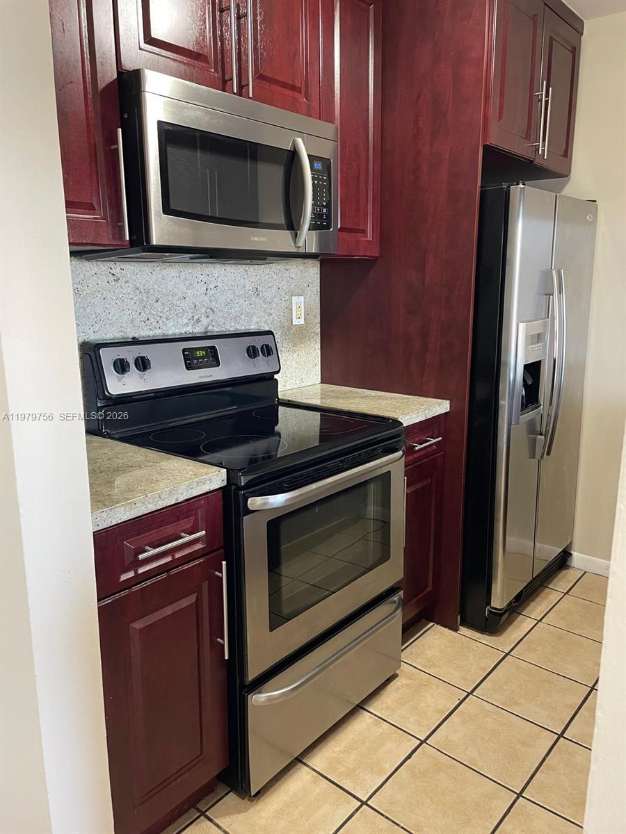 8002 Southwest 149th Avenue, Unit B409 Miami, FL 33193 - Photo 4 of 23 a kitchen with stainless steel appliances granite countertop a stove microwave and refrigerator