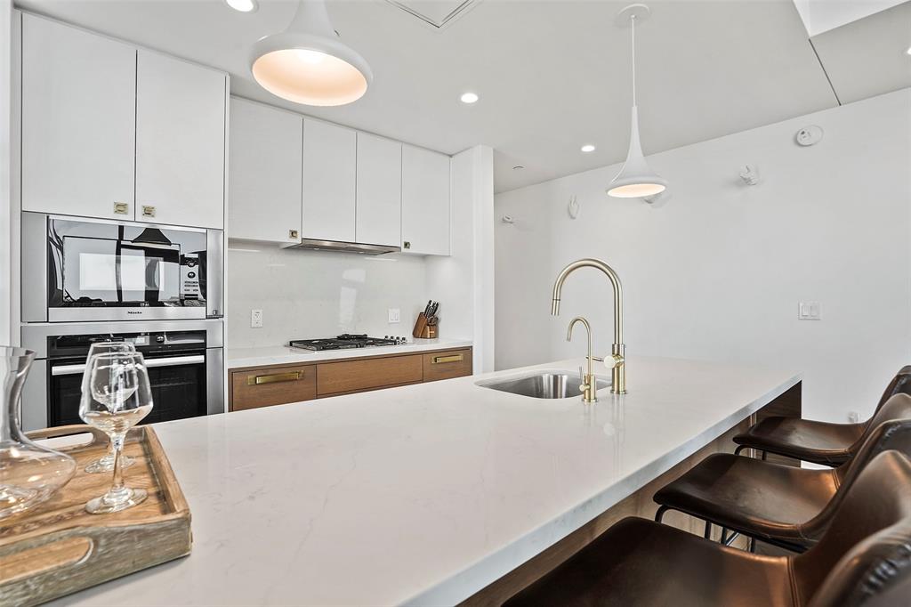 70 Rainey Street, Unit 1409 Austin, TX 78701 - Photo 10 of 38 Kitchen with pendant lighting, a kitchen bar, light stone counters, dual tone cabinets, and stainless steel appliances