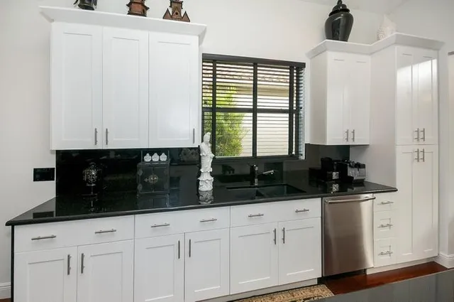 a kitchen with white cabinets and window