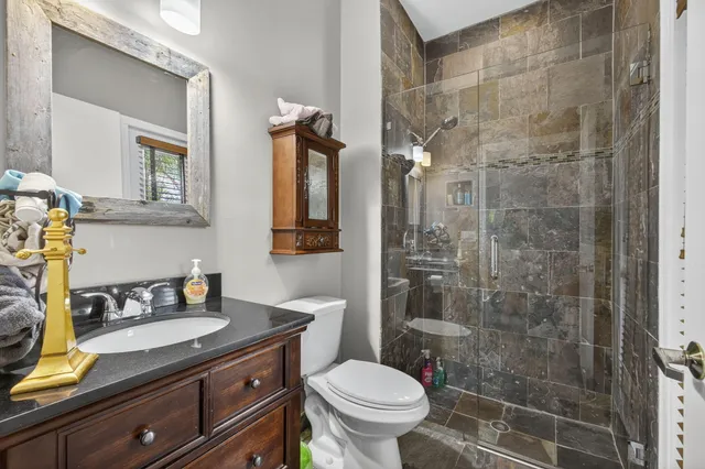 a bathroom with a granite countertop sink a toilet a mirror and shower