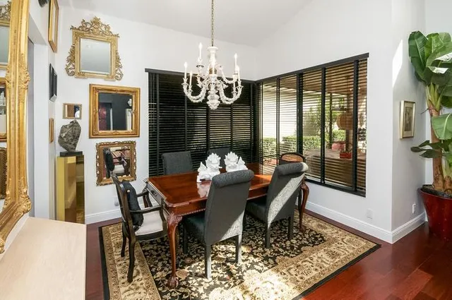 a dining room with furniture large windows a chandelier and wooden floor