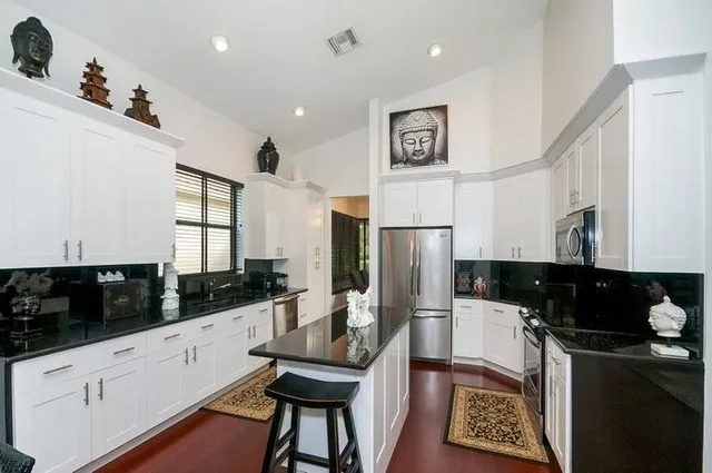 a kitchen with stainless steel appliances kitchen island granite countertop a refrigerator and a sink