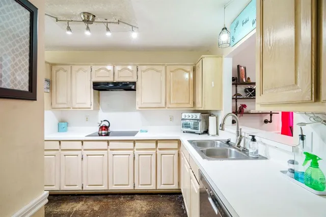 a kitchen with stainless steel appliances granite countertop a sink dishwasher and white cabinets with wooden floor