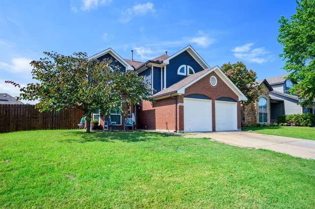 a front view of house with yard and trees in the background