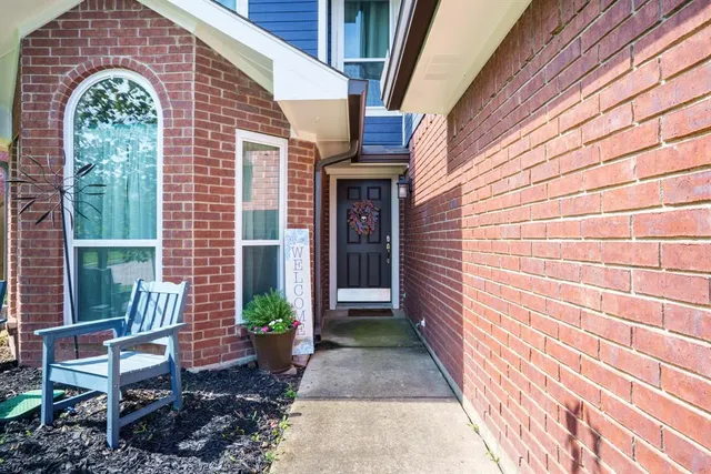 a view of a brick house with a chairs and table in a patio
