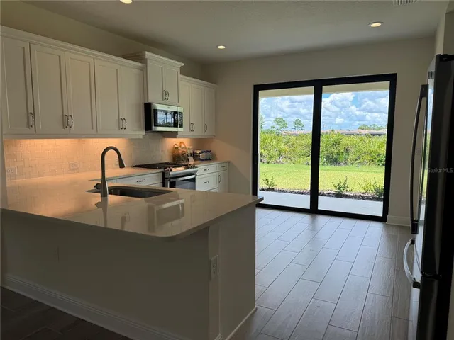 a kitchen with sink a large window and cabinets