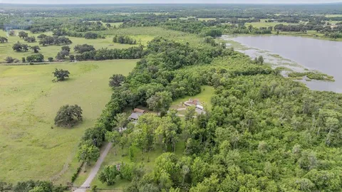 an aerial view of green landscape with trees houses and lake view
