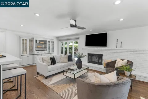 a living room with furniture a wooden floor and kitchen view