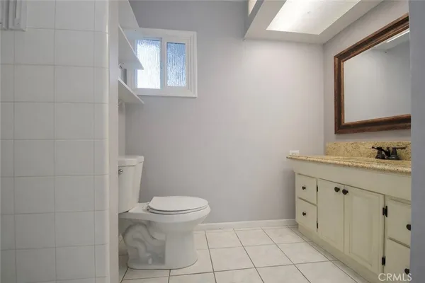 a bathroom with a granite countertop toilet a sink a mirror and a window