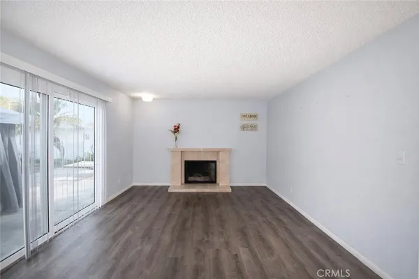 an empty room with wooden floor fireplace and windows