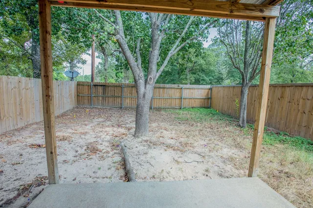 a view of a backyard with a trees and wooden fence