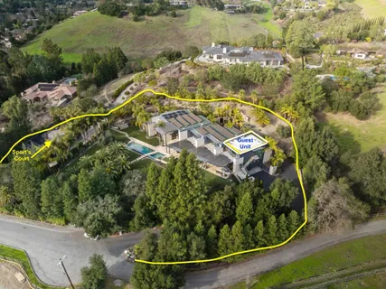 an aerial view of a residential houses with outdoor space and trees