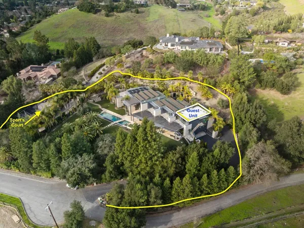 an aerial view of a residential houses with outdoor space and trees