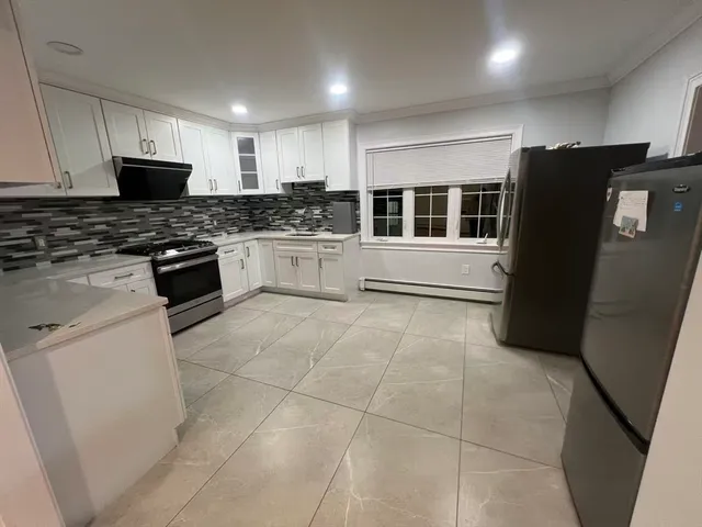 a kitchen with a refrigerator and white cabinets