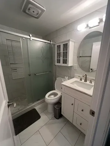 a bathroom with a granite countertop sink toilet a mirror and shower