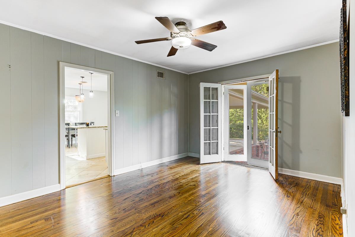 5676 Barfield Road Memphis, TN 38120 - Photo 9 of 19 Interior room featuring rich wood-finish flooring, light grey wall paneling, and a ceiling fan with integrated lighting