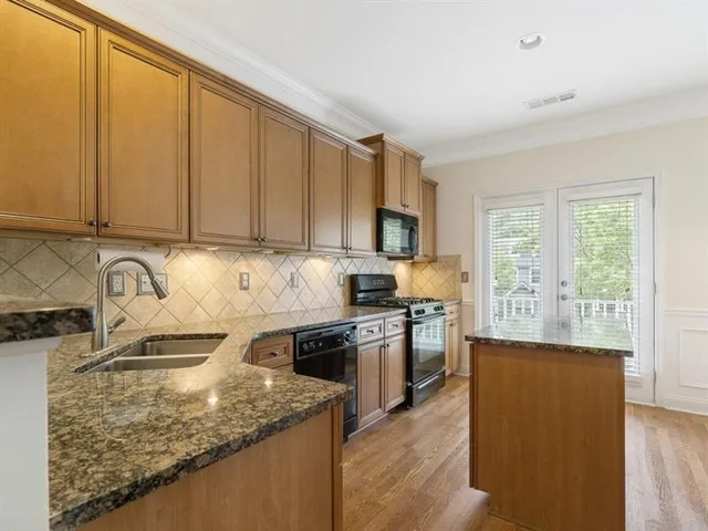 a kitchen with granite countertop a stove sink and microwave