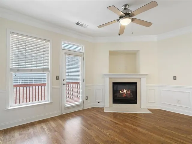 a view of an empty room with wooden floor fireplace and a window