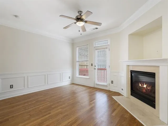 a view of an empty room with wooden floor fireplace and a window