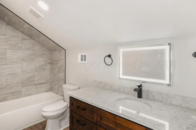 a bathroom with a granite countertop sink a toilet and a bathtub