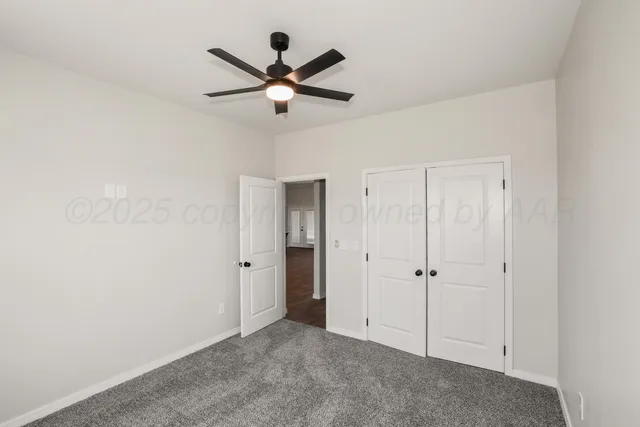 an empty room with closet and a ceiling fan