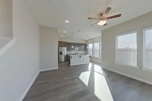 a view of a hallway with wooden floor and a kitchen