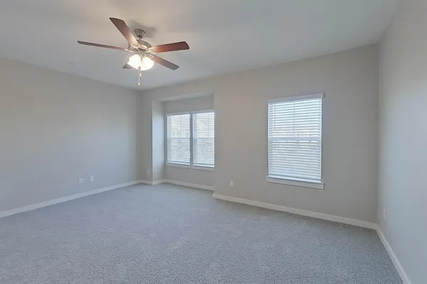 an empty room with windows and fan