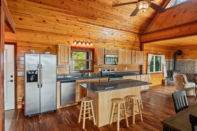 a kitchen with stainless steel appliances granite countertop a table chairs refrigerator and sink