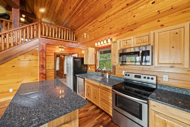 a kitchen with stainless steel appliances kitchen island granite countertop a stove a sink and a microwave