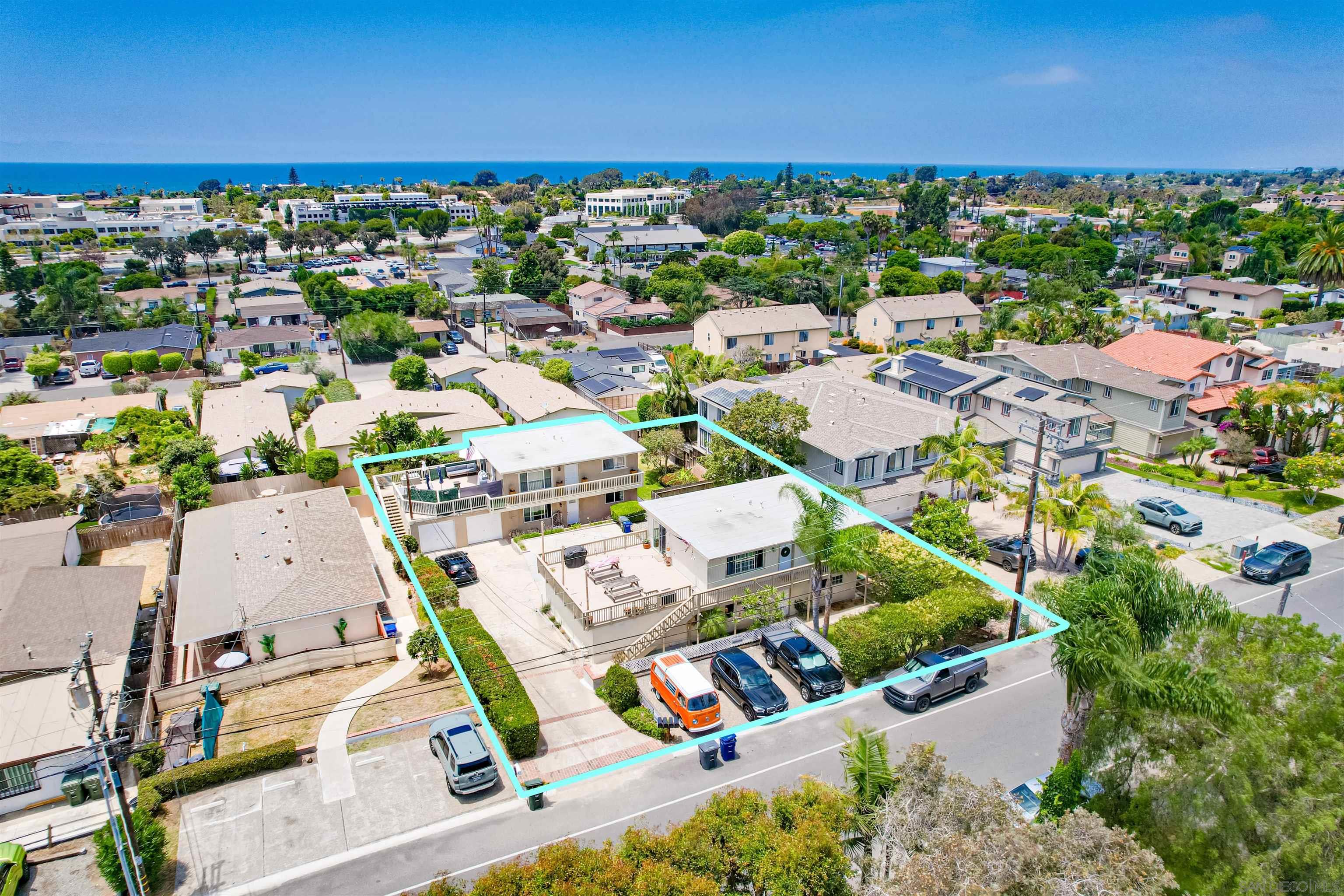 an aerial view of residential houses with outdoor space and ocean view