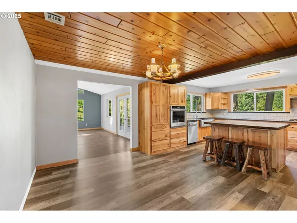 an empty room with wooden floor chandelier and windows