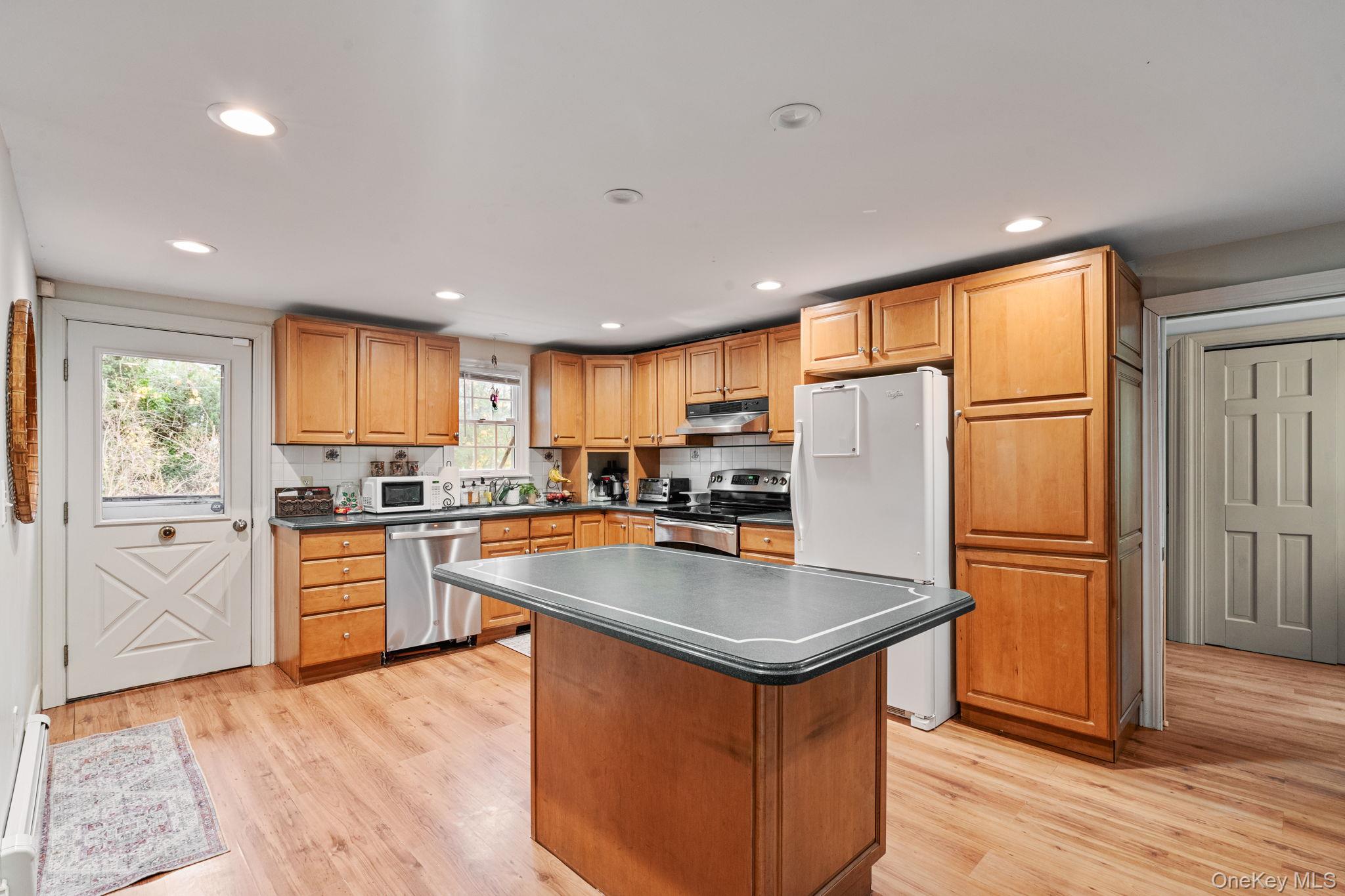 170 North Country Road Miller Place, NY 11764 - Photo 9 of 48 a kitchen with stainless steel appliances granite countertop a refrigerator a sink dishwasher a stove and white countertops with wooden floor