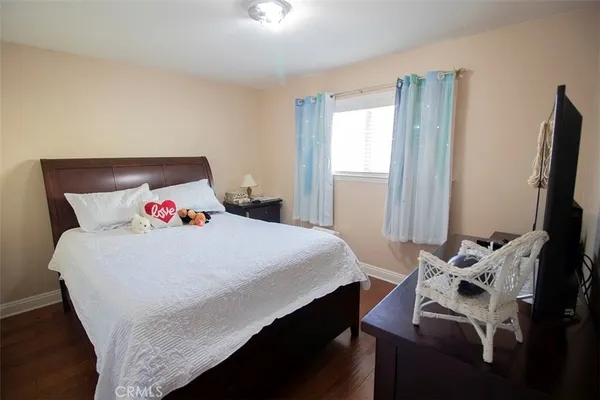a bedroom with a bed and a flat tv screen on a dresser