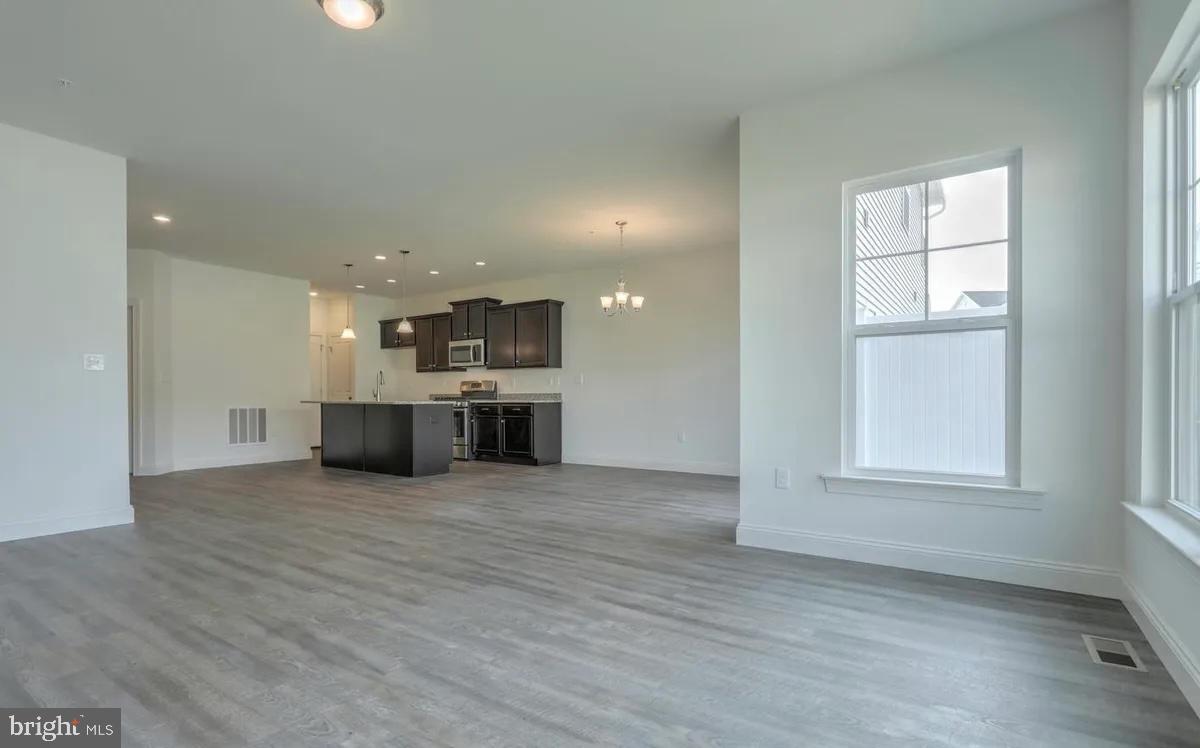 4118 Orrs Bridge Road, Unit 27 Mechanicsburg, PA 17050 - Photo 12 of 18 an empty room with wooden floor kitchen view and windows