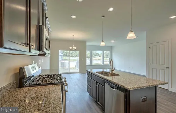 a kitchen with stainless steel appliances granite countertop a sink a stove and a wooden floors