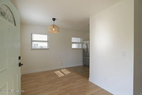 an empty room with wooden floor cabinet and windows