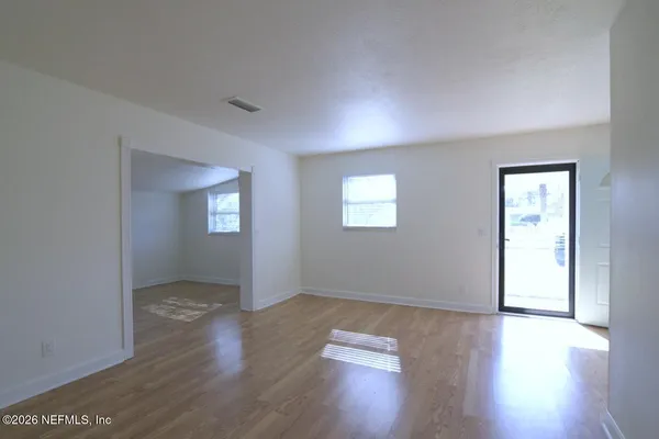 a view of an empty room with wooden floor and a window