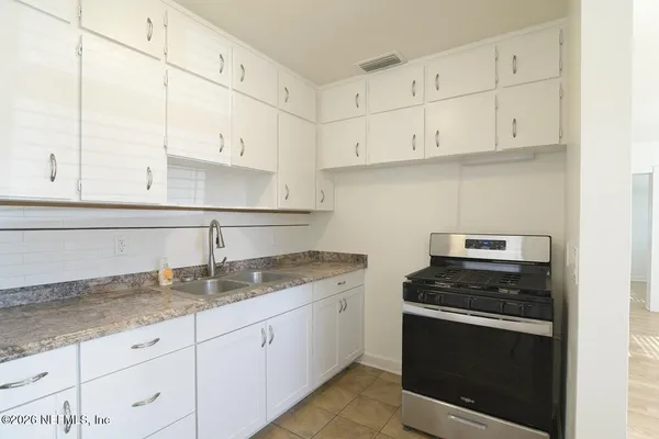 a kitchen with granite countertop white cabinets and a stove