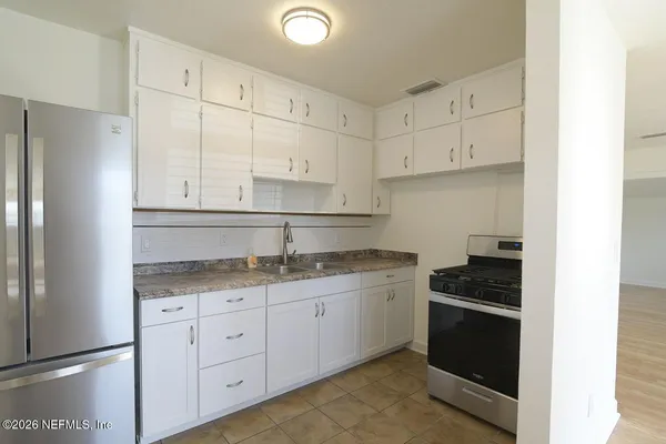 a kitchen with granite countertop white cabinets and refrigerator