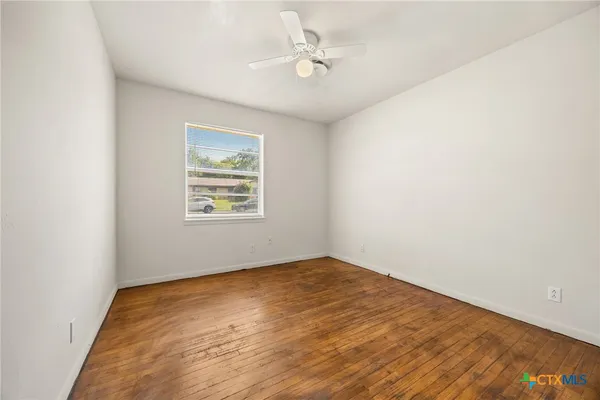 an empty room with a window and a ceiling fan