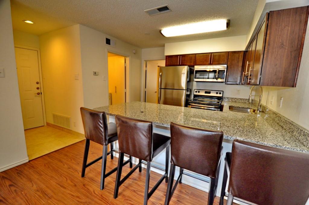 a kitchen with stainless steel appliances granite countertop table chairs sink refrigerator and microwave