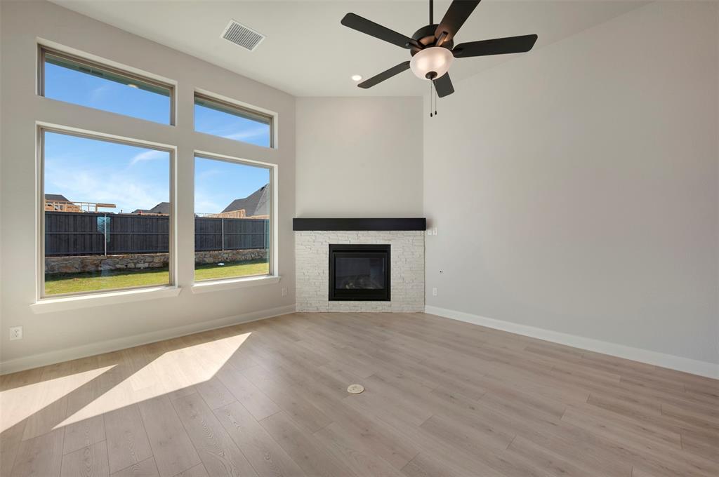 3575 Redbud Flower Trail Venus, TX 76084 - Photo 23 of 36 Unfurnished living room featuring ceiling fan, a stone fireplace, and light wood finished floors