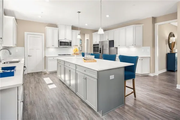 a kitchen with stainless steel appliances a stove a sink a refrigerator and white cabinets with wooden floor