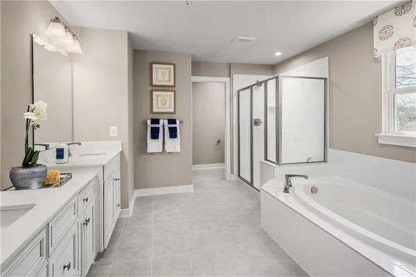 a spacious bathroom with a double vanity sink a mirror a bathtub and next to a window