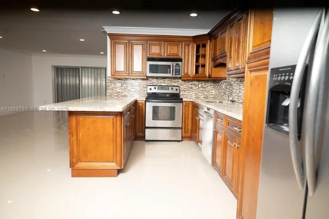 a kitchen with stainless steel appliances granite countertop a stove a sink and a refrigerator