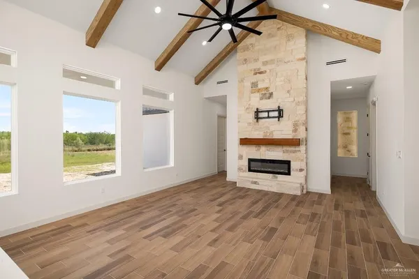 an empty room with windows a fireplace a ceiling fan and wooden floor