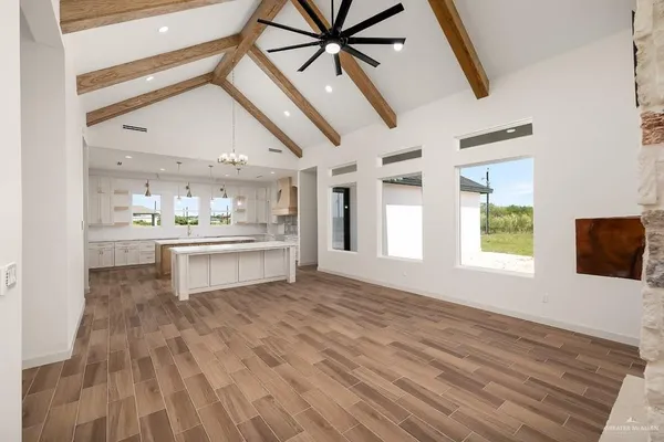 a view of a kitchen with kitchen island a window wooden floor and stainless steel appliances