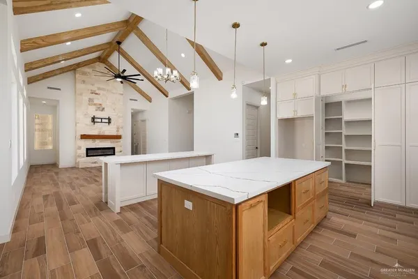 a kitchen with a stove a sink a center island and a wooden floor