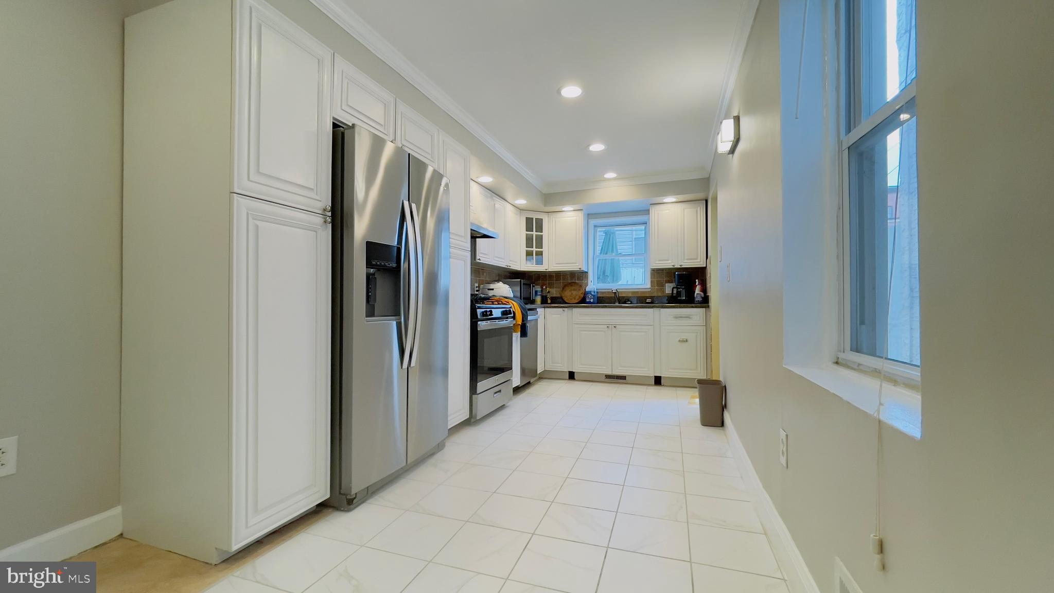 a view of a kitchen with refrigerator and white cabinets